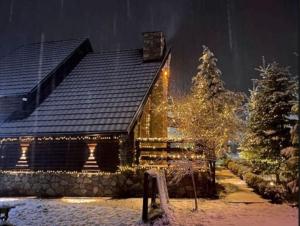 una casa cubierta de luces de Navidad en la nieve en Green Villa Brezovica, en Štrpce