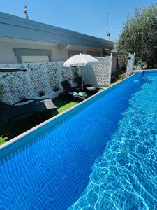 een groot blauw zwembad met een parasol en stoelen bij La Casetta tra Sassi e Ulivi B&B in Matera