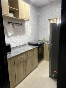 a kitchen with wooden cabinets and a black refrigerator at Beautiful 2Br Apt in Ogba, Ikeja, Lagos in Lagos
