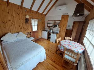 ein Schlafzimmer mit einem Bett und einem Tisch sowie eine Küche in der Unterkunft L'Emiliano Cabañas-Ristorante in Capitán Pastene
