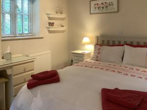 ein Schlafzimmer mit einem weißen Bett mit roten Handtüchern darauf in der Unterkunft Rustys Cottage in Skirpenbeck