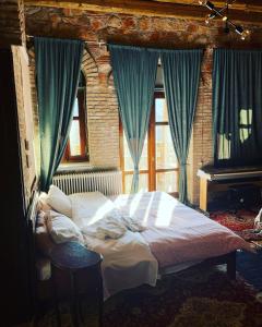 een slaapkamer met een bed met blauwe gordijnen en een piano bij Lykos Mansion in Kápsas