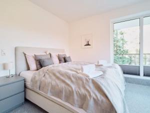 a white bedroom with a large bed and a window at Ferienwohnung "Gilde" hyggelig mit Blick ins Grüne in Glücksburg