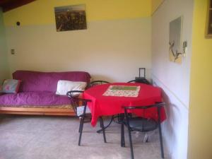 sala de estar con mesa roja y sofá en Cabaña en las sierras de Cosquín en Cosquín