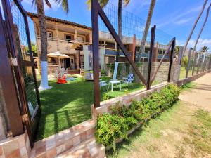 a fence with a yard with palm trees and a building at Casa à beira mar de Maragogi com 3 quartos, 4 banheiros e Área Verde in Maragogi