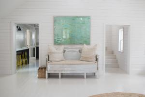 Habitación blanca con banco y pintura en la pared en Conch Shell Harbour Island home, en Harbour Island