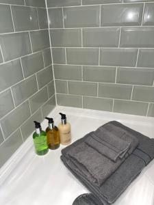 a bathroom sink with two towels and two bottles of soap at Acaster House, Rooms 1 to 5, free parking, SUPER fast wi-fi, en-suite, corporates welcome in Kettering