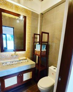 a bathroom with a sink and a toilet and a mirror at White Hut Villas by Asog resort in Naga