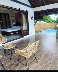 a patio with chairs and a bed and a pool at White Hut Villas by Asog resort in Naga