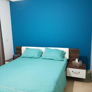 a bedroom with a blue wall and a bed at place to be perla 2 saidia in Saïdia