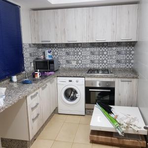 a kitchen with a washing machine and a microwave at place to be perla 2 saidia in Saïdia