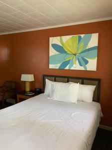 ein Schlafzimmer mit einem weißen Bett und einem Gemälde an der Wand in der Unterkunft The Triangle Motel in Alma