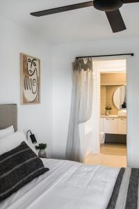a bedroom with a white bed with a ceiling fan at The Beach Retreat offers Pool and River Views in Noosa Heads +32 photos