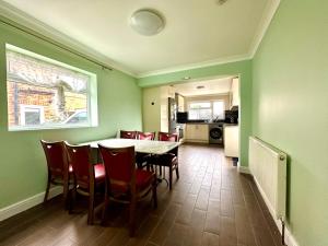 uma sala de jantar com paredes verdes e uma mesa e cadeiras em Spacious 3 double bedroomed house in Bicester em Bicester