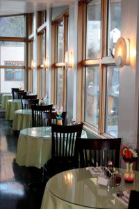 uma sala de jantar com mesas, cadeiras e janelas em The Driftwood Lodge em Juneau
