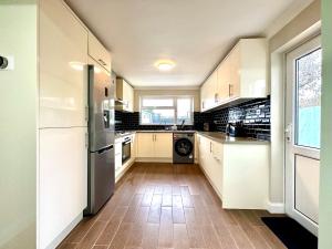 uma cozinha com armários brancos e uma grande janela em Spacious 3 double bedroomed house in Bicester em Bicester