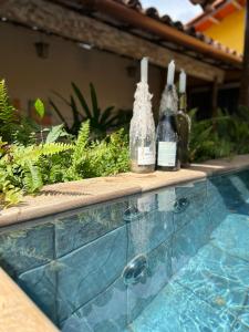 três garrafas de vinho sentadas numa saliência ao lado de uma piscina em Chalés na Roça em Pirenópolis