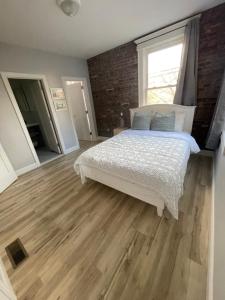 1 dormitorio con cama blanca y pared de ladrillo en Modern Luxury Apartment near NYC, en Jersey City