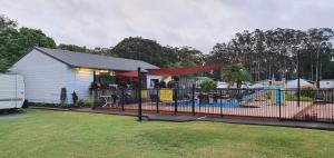 un edificio con una valla junto a un parque infantil en Sunset Caravan Park Woolgoolga en Woolgoolga