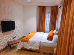 una camera con letto e TV a parete di Akura Villa Adeniyi Jones Ikeja a Ikeja