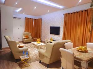 un soggiorno con sedie, tavolo e TV di Akura Villa Adeniyi Jones Ikeja a Ikeja