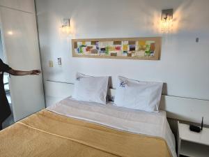 um quarto com uma cama com lençóis brancos e almofadas em Belíssimo frente mar 107 em Fortaleza