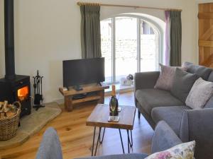 a living room with a couch and a fire place at Spindle Well Barn in Elsdon