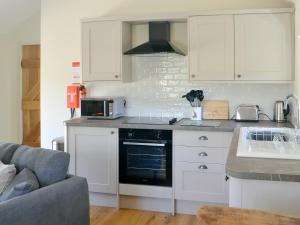 a kitchen with white cabinets and a stove top oven at Spindle Well Barn in Elsdon