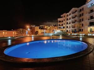 ein großer blauer Pool in der Nacht mit Gebäuden in der Unterkunft Garajau Terrace Adventure-Pool and Free Parking in Caniço