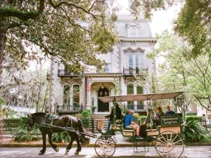 a horse drawn carriage in front of a house at Southern Charmer-Historic District Downtown-Peaceful Private Porch-Walk Score 90!! in Savannah