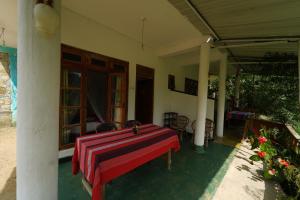 a house with a red table on the front porch at Nature's Glow Home Stay AND RESTAURANT in Ella