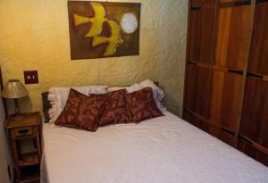 1 dormitorio con 1 cama blanca y 2 almohadas en Chalé vista exuberante na Serrinha do Alambari, en Resende