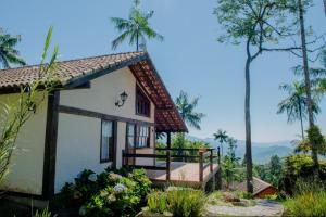 Casa pequeña con balcón y palmeras en Chalé vista exuberante na Serrinha do Alambari, en Resende