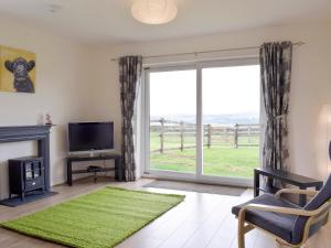 a living room with a tv and a large window at Barley Heights in Hapton