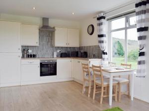a kitchen with white cabinets and a table and chairs at Barley Heights in Hapton