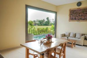 a dining room with a table and a large window at Kidupa Villa in Ubud
