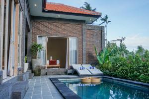 a house with a swimming pool next to a building at Kidupa Villa in Ubud