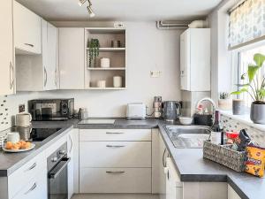 a kitchen with white cabinets and a sink at Driftwood Cottage in Gorleston-on-Sea
