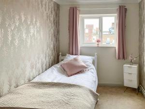 a bedroom with a bed with a pink pillow on it at Driftwood Cottage in Gorleston-on-Sea