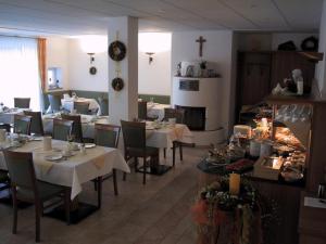 a restaurant with tables and chairs and a cross on the wall at Gästehaus am Rastberg in Langenbach