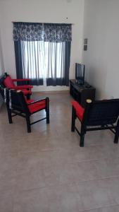Sala de estar con 2 sillas rojas y TV en Alojamientos Malargüe en Malargüe