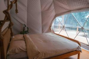 a bedroom with a canopy bed with a large window at Romantic DOME with hot jacuzzi and Jungle view in Klungkung