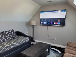 uma sala de estar com um sofá e uma televisão de ecrã plano em No Chores, 10min to downtown and 25min to Niagara Falls em Buffalo