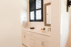 Baño blanco con lavabo y espejo en Haven House en Pensacola