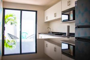 a kitchen with white cabinets and a large window at Departamento Olas in Tuxtla Gutiérrez +3 photos