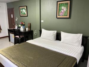a large bed in a room with a desk at Baan Klang Vieng in Chiang Mai