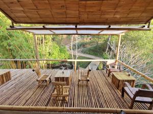 a deck with chairs and tables and a roof at Harvest Moon Valley in Ban Pang Luang