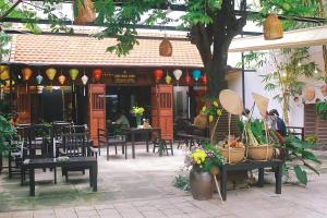 un restaurant avec des tables, des chaises et un arbre dans l'établissement Davue Hotel by THG, à Đà Nẵng