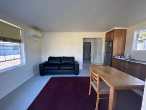 a living room with a black couch and a table at Glenaire Apartments at Frazer St in Strahan