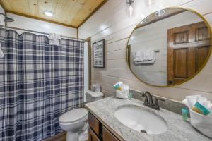 La salle de bains est pourvue d'un lavabo, de toilettes et d'un miroir. dans l'établissement Osprey Nest Cottage Modern New Cabin, à Pigeon Forge